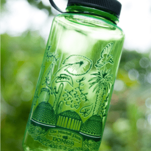 A green, reusable plastic water bottle with nature-themed illustrations, including trees, birds, plants, and a dome-like structure. The artwork has text that reads "The Mitchell Park Domes," with a focus in the foreground and a blurred leafy background.